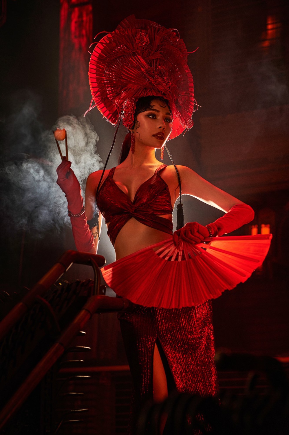Performer in a red fan headdress holding a red fan as steam rises, Steam Room at Sing Sing Theater, Bangkok
