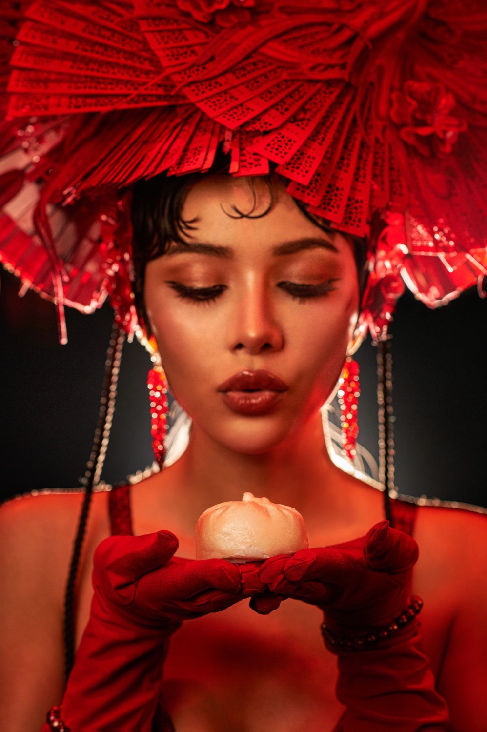 Performer in a red fan headdress holding a bao, Steam Room dim sum supperclub, Bangkok