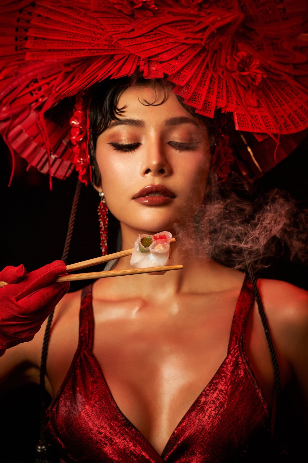 Performer tasting a dim sum with chopsticks as steam rises, Steam Room, Sing Sing Theater